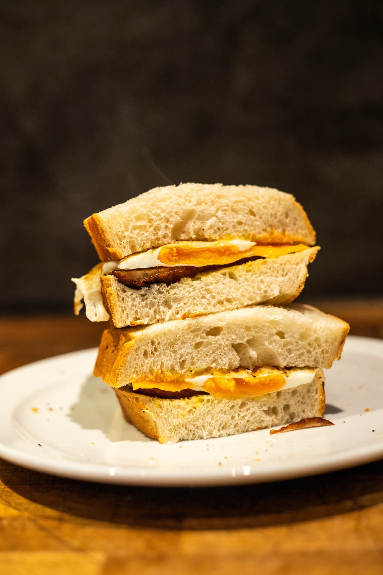 Bacon and fried egg sandwich on thick white bread, cut in half
